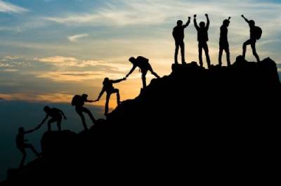 silhouettes d'une équipe s'entraidant à atteindre un sommet