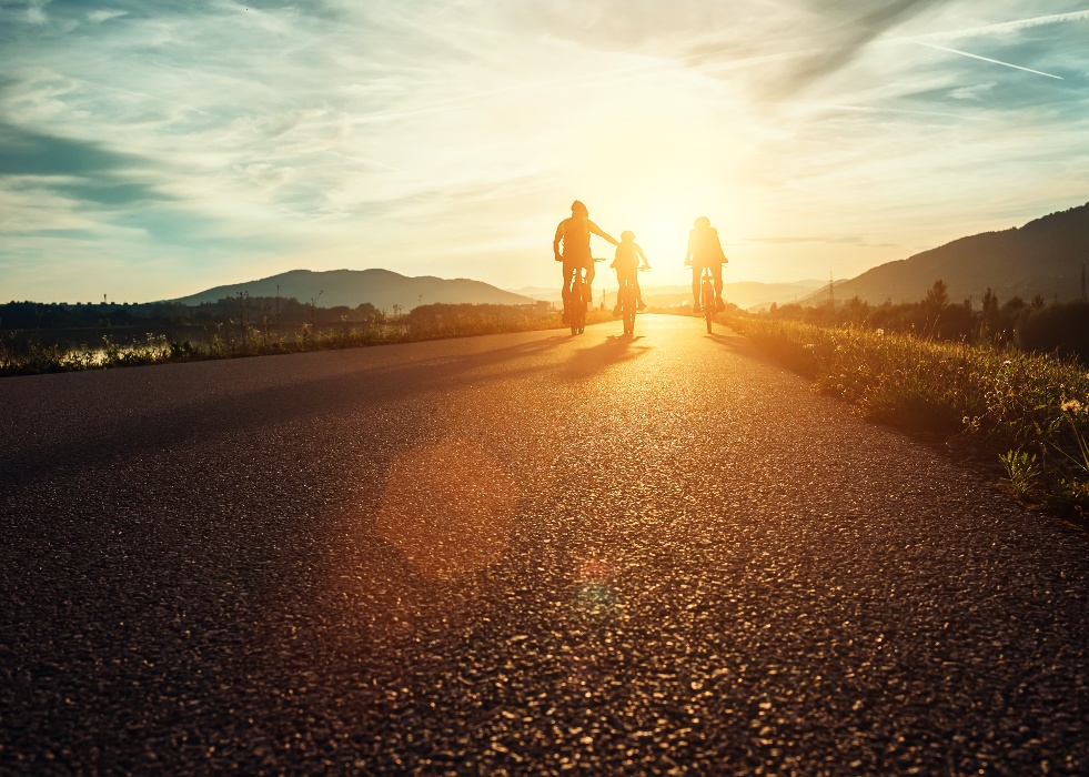 trois personnes roulant à velo vers le soleil couchant