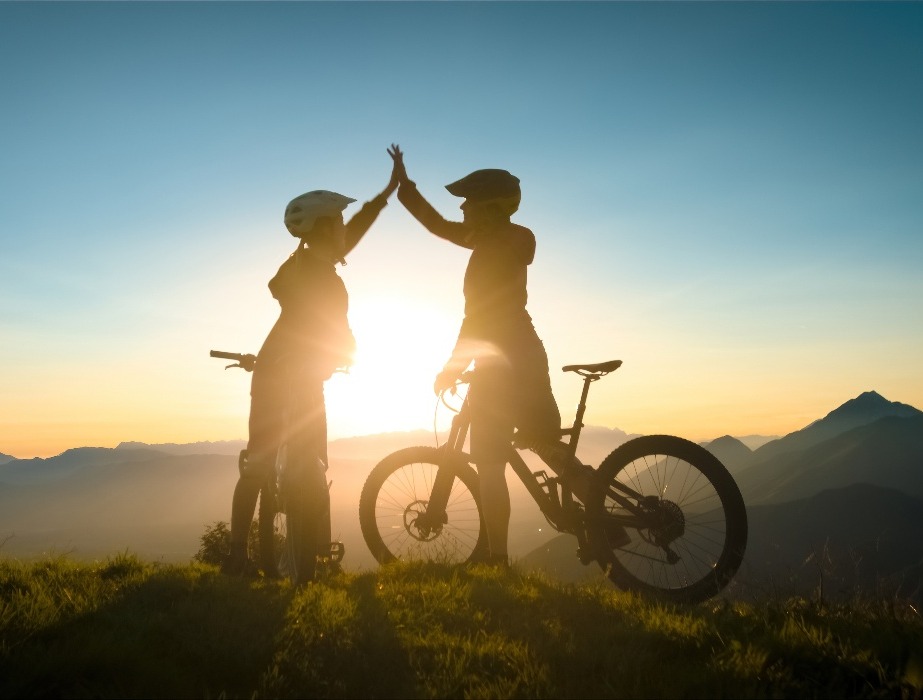 deux cyclistes se tapant dans la main ayant réussi leur objectif