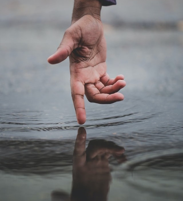 main tendue se reflétant dans l'eau